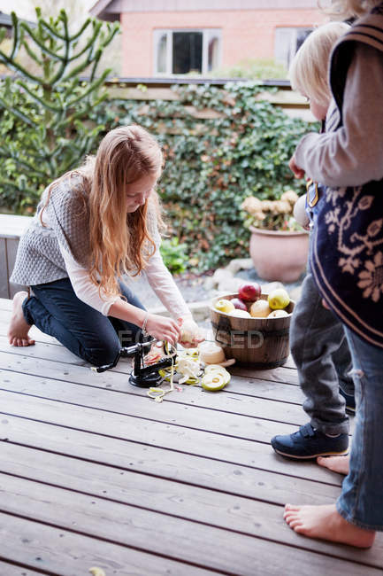 Девушка чистит фрукты на патио — стоковое фото