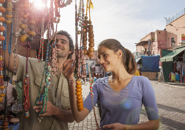 Молодая пара на рынке глядя на бусы, Джемаа эль-Fnaa площади, Марракеш, Марокко — стоковое фото