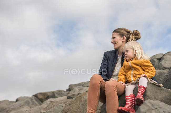 Madre y niño sentado en piedras - foto de stock