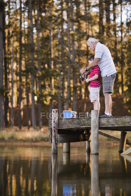 Мальчик рыбачит с дедушкой в озере — стоковое фото