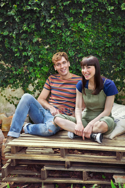 Young couple sitting on wooden palettes — Stock Photo
