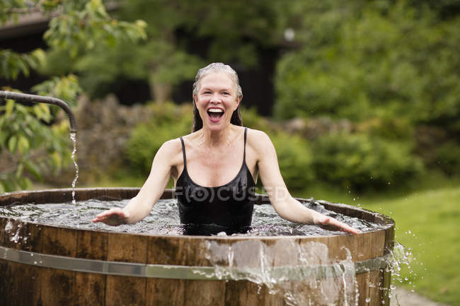 Mujer madura de pie en la bañera de agua fría fresca en eco retiro - foto de stock