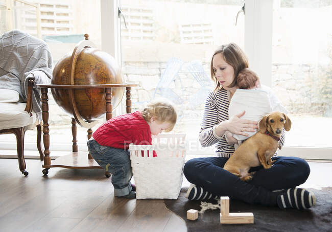 Boy playing at home with mother and baby sister — Stock Photo