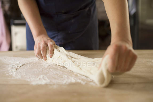 Abgeschnittenes Bild vom Bäcker, der Brotteig streckt — Stockfoto