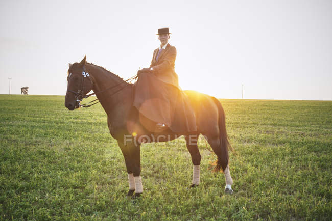 Portrait of dressage horse and rider training in field at sunset — Stock Photo