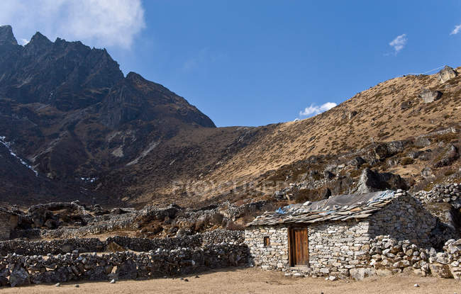 Кам'яний будинок у пиловій гірській долині під блакитним небом — стокове фото