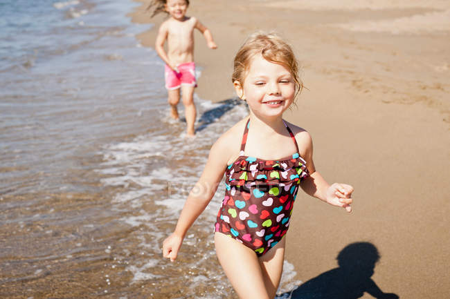Ragazze sorridenti che giocano in onde sulla spiaggia — Foto stock