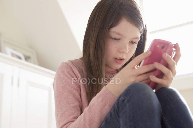 Fille assise regardant smartphone à la maison — Photo de stock