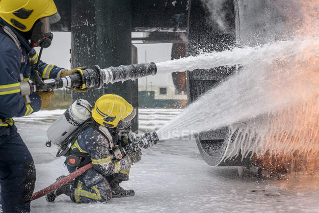Feuerwehrleute versprühen Wasser bei simuliertem Flugzeugbrand auf Ausbildungsstätte — Stockfoto