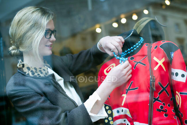 Mujer poniendo collar en tienda maniquí - foto de stock