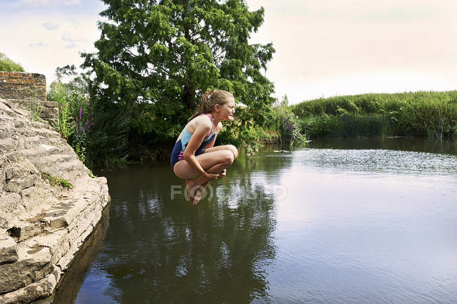 Vue latérale de fille sautant dans le lac — Photo de stock
