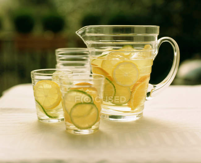Brocca di limonata e bicchieri sul tavolo con frutta fresca — Foto stock