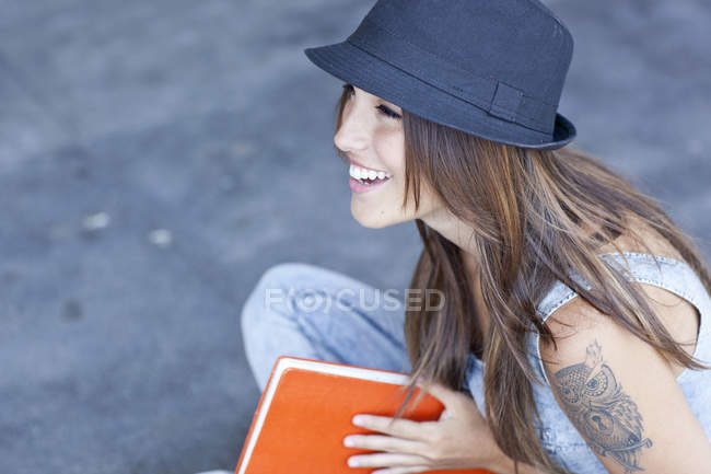 Mujer estudiante usando sombrero celebración libro - foto de stock