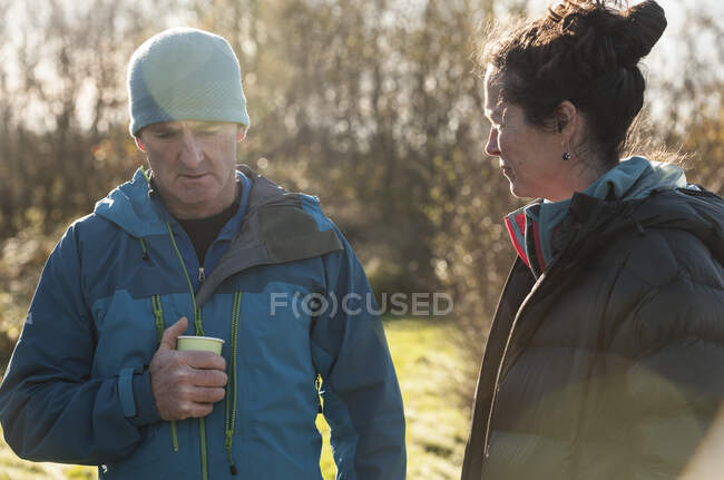 Зрелые мужчина и женщина в пальто на солнце — стоковое фото