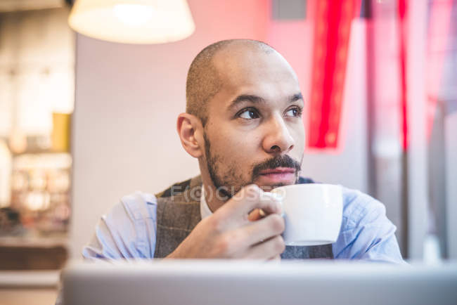 Empresario bebiendo café y usando portátil en la cafetería - foto de stock