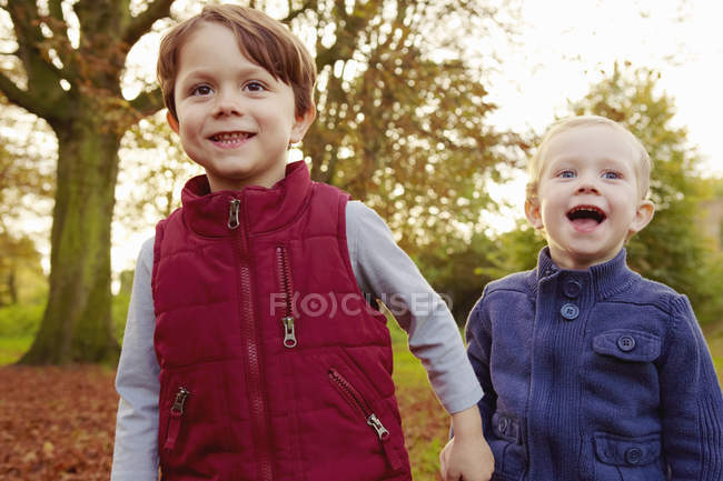 Brothers holding hands while walking in park — Stock Photo