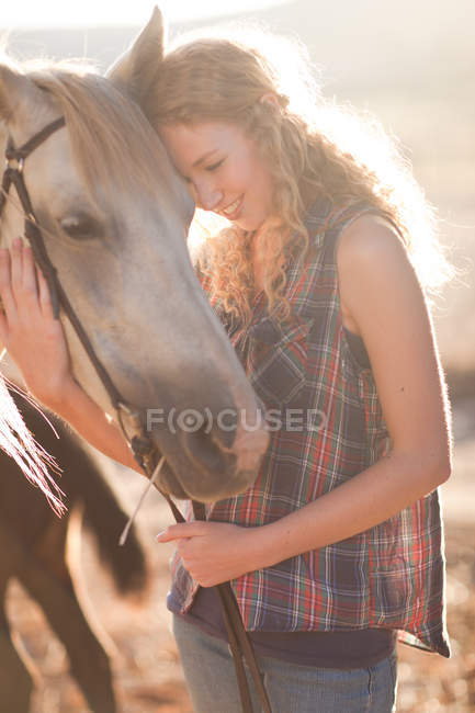 Giovane donna che tocca il viso di cavallo — Foto stock