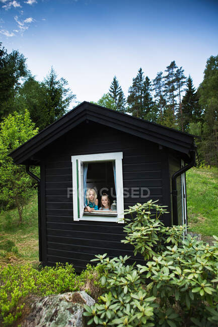 Meninas olhando pela janela da cabana — Fotografia de Stock