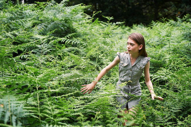 Teenage girl walking through bracken in forest — Stock Photo
