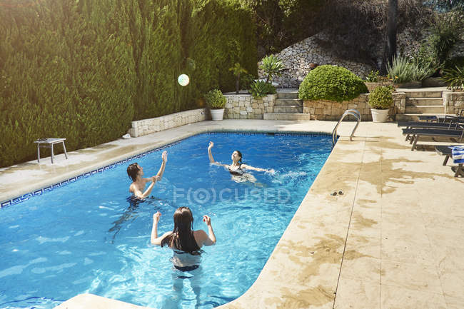 Mature woman throwing ball with son and daughter in swimming pool — Stock Photo