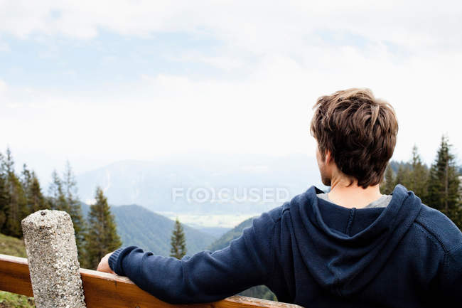 Homme assis sur le banc et regardant le paysage — Photo de stock
