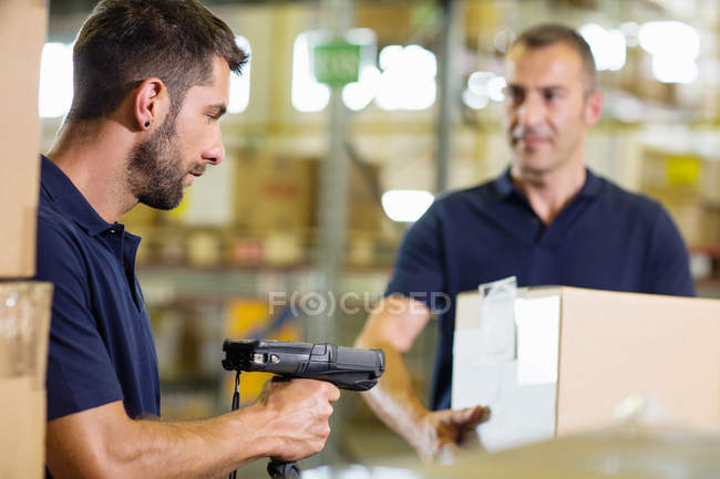 Deux employés d'entrepôt utilisant un scanner de codes à barres dans un entrepôt de distribution — Photo de stock