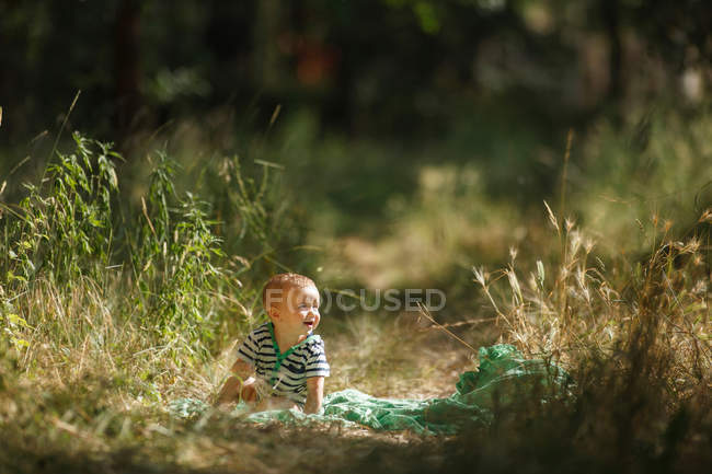 Criança sentada em cobertor no campo — Fotografia de Stock