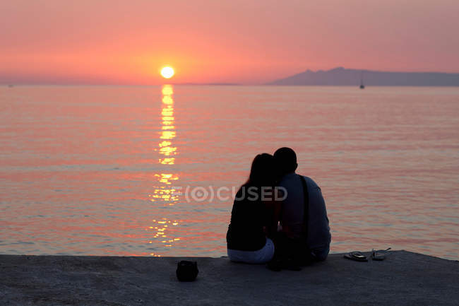 Пара розслабляється на пірсі на заході сонця — стокове фото