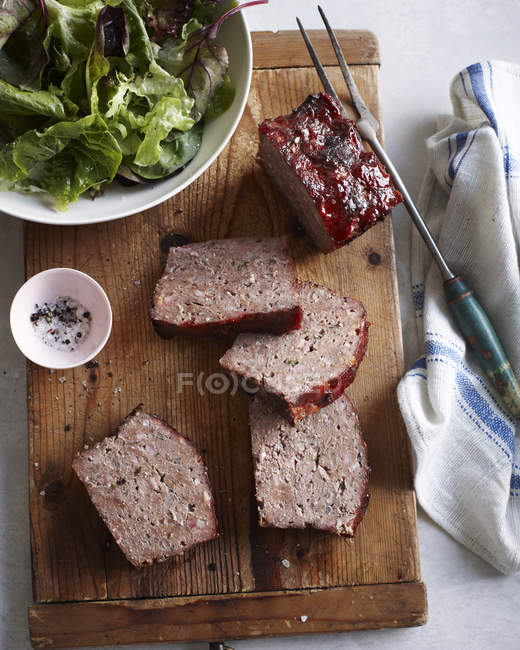 Vista superior de rolo de carne clássico e tigela de salada na tábua de corte — Fotografia de Stock