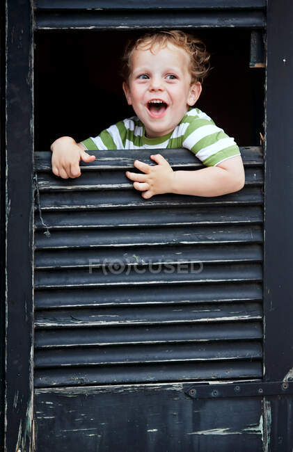Bambino ragazzo peeking fuori da finestra — Foto stock