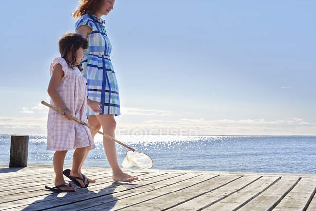 Mother and daughter on pier with fishing net — Stock Photo