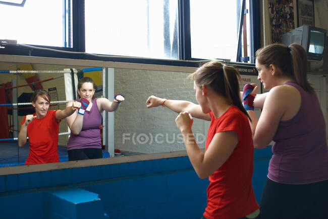 Entrenamiento de boxeador con entrenador en gimnasio - foto de stock