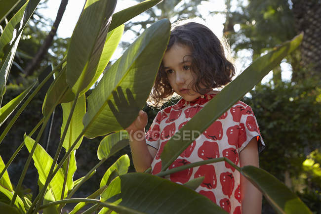 Bambina con espressione pensierosa in piedi tra le foglie — Foto stock