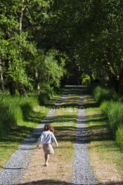 Chica caminando en camino rural - foto de stock