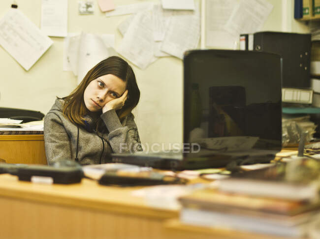 Jeune femme ennuyée au bureau appuyée sur le coude — Photo de stock