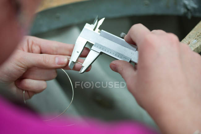 Woman measuring metal wire for jewelry — Stock Photo