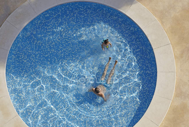 Overhead view of man and toddler daughter in swimming pool — Stock Photo