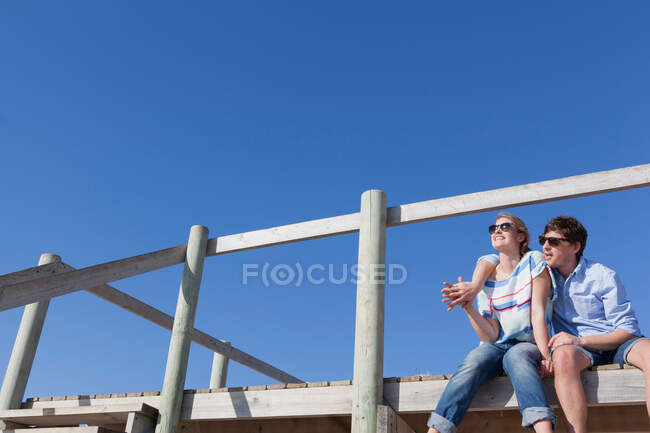 Pareja sentada en el paseo marítimo, ángulo bajo - foto de stock