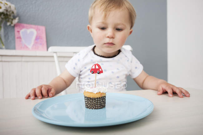 Junge schaut sich Cupcake an — Stockfoto