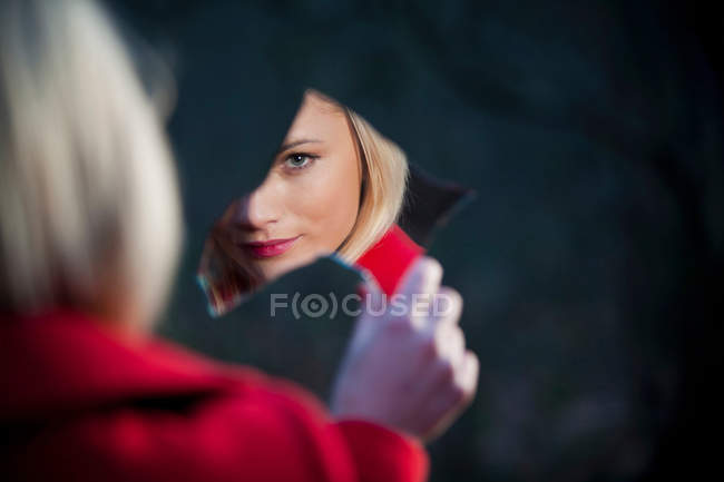 Woman admiring herself in mirror shard — Stock Photo