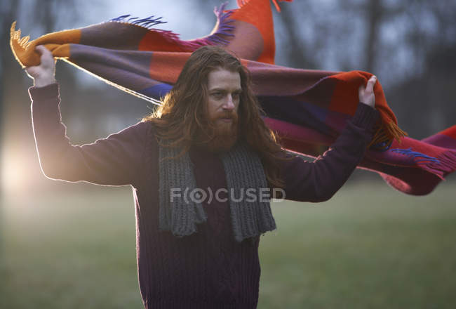 Man wrapping blanket around himself in countryside — Stock Photo