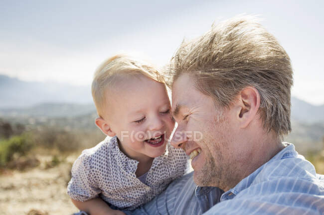 Hombre maduro e hija pequeña riendo, Calvi, Córcega, Francia - foto de stock