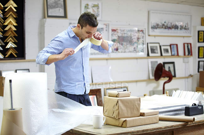 Mann mit Luftpolsterrahmen auf Tisch in Bilderrahmen-Werkstatt — Stockfoto