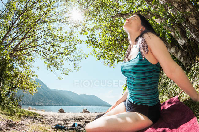 Усміхається жінка, сидячи на сільських озера — стокове фото