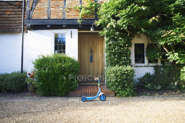 Side view of toy scooter parked outside cottage — Stock Photo