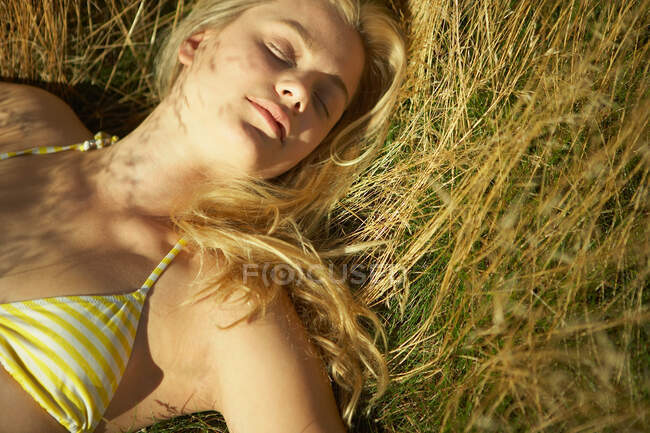 Jovem deitada em grama longa — Fotografia de Stock