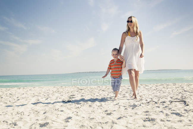 Mãe e filho passeando na praia de areia — Fotografia de Stock