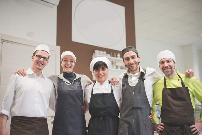 Bakers and waiters posing in a row at cafe — Stock Photo