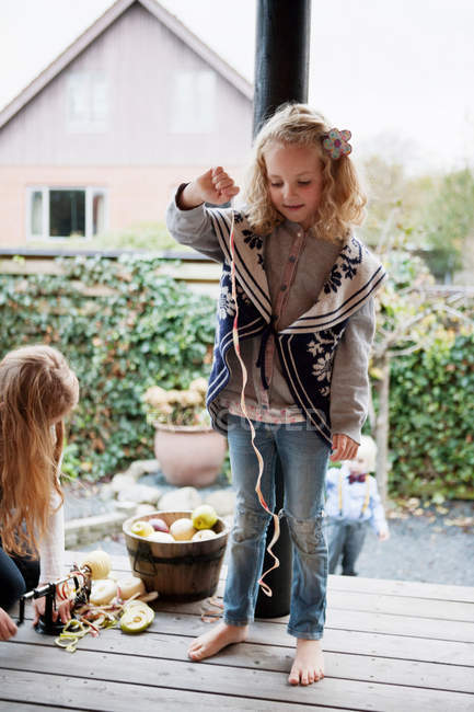 Девушка играет с фруктовой кожурой на патио — стоковое фото