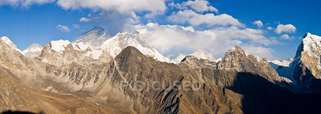 Rocky mountaintops covered with snow and cloudy sky — Stock Photo